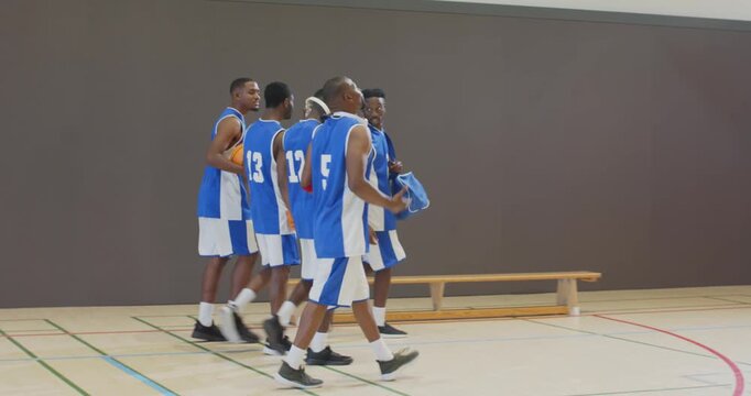 Spotting red exit door, african american basketball team walking sideline and grabbing ball
