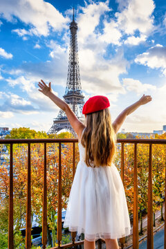 Rear view of a happy girl with a red beret hat looking at the Eiffel Tower of Paris, France