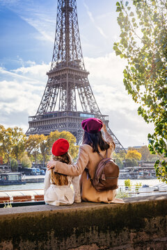 Family city travel concept with a mother and her daughter looking at the beautiful riverbank view of the Eiffel Tower in Paris, France