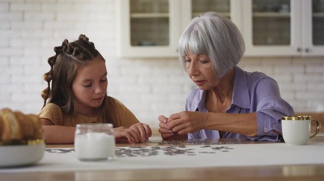 Grandmother and her granddaughter connecting jigsaw puzzle pieces together