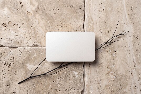 Blank luxury business card with rounded corners on travertine stone slabs with black dried branch, premium paper mockup flat lay copy space