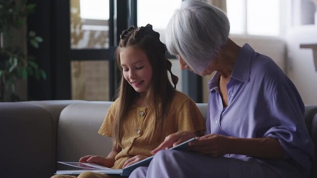 Girl and her granny looking at photos in an album, family tree, happy memories