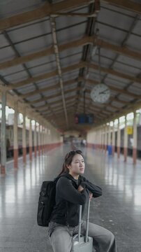 Traveler sitting with luggage at a train station, ideal for waiting, departure, rail travel, tourism, solo journey, public transport and travel lifestyle concepts.
