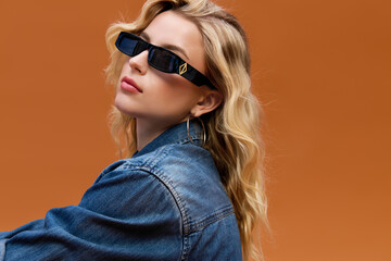 Naklejka premium Blonde woman showcases her denim style against a bright backdrop