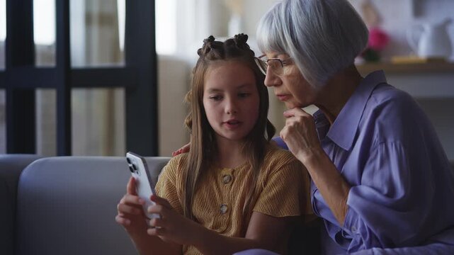 Girl explaining to her granny how to create a social media account on a phone