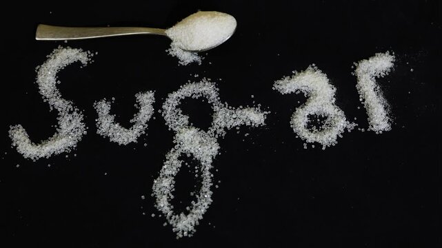 sugar text made from granulated sugar crystals with spoon symbolizing sweetness and nutrition topic