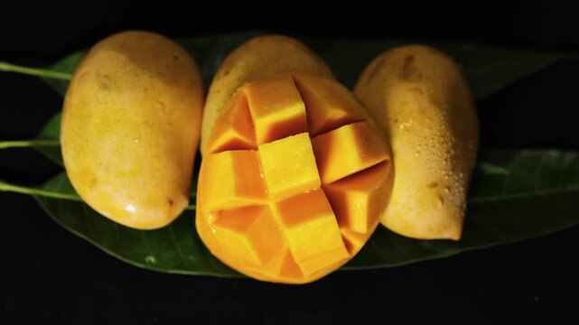 delicious ripe mango prepared in hedgehog cut style with natural green leaf backdrop