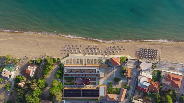 Static overhead drone shot of Kourouta beach, Greece. Dexamenes Seaside Hotel umbrellas, bathers on shore, swimmers in sea