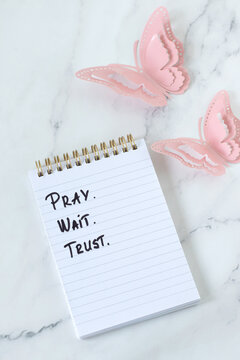 Pray, wait, trust, christian encouragement text in a notebook. Biblical concept of patience and faith in God Jesus Christ.