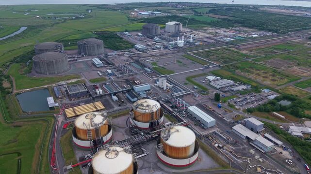 Aerial view of the Liquified Natural Gas LNG Terminal with large storage tanks and industrial infrastructure surrounded by green fields in Isle of Grain, England, United Kingdom.
