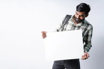 Young indian man showing empty board on white background © PRASANNAPIX