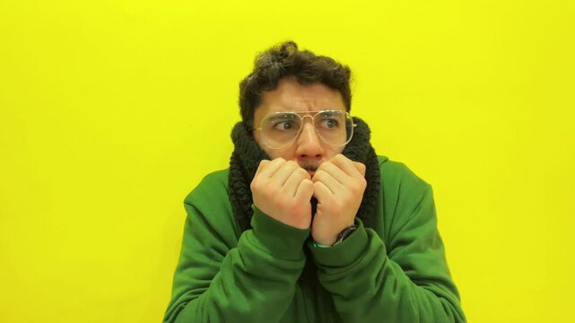 Scared and anxious young man expressing fear against a yellow background