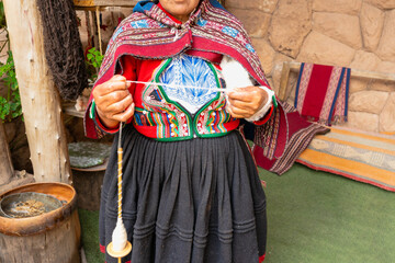 Obraz premium Close-up of Andean craftswoman spinning wool with drop spindle in rural Peru