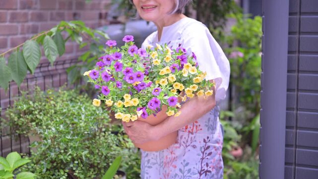 庭の花に水やりをする顔無しのクローズアップ　園芸やお花屋さんなどの花壇のイメージの動画