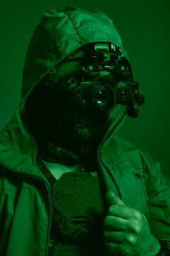 Tactical operator in civilian jacket with hybrid thermal imaging monocular and night vision goggles system, authentic green phosphor NVG grain effect