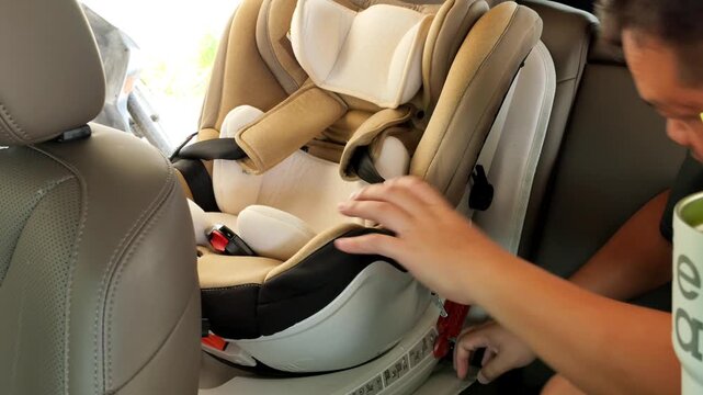 A man checks the installation of a child car seat in the backseat of a vehicle, ensuring proper fit. Useful for parenting guides or safety demonstrations.