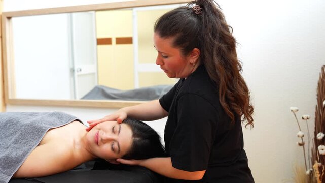 Professional female osteopath massaging a woman's head and neck in a wellness center