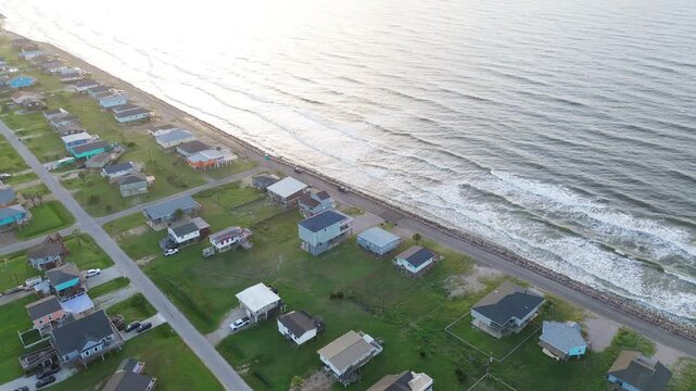 Beachside parallel lanes show rows of homes east of Seashell Dr aligned with shoreline road tracing Surfside Beach waterfront toward jetty. Soft highlights on roofs coastal blocks, Freeport, TX