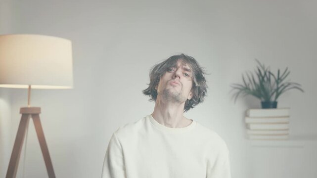 Young man sitting in oversized sweater, casual indoor portrait in modern minimalist home