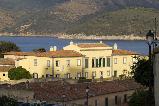 View of the historic Villa dei Mulini, former Napoleons home, with its yellow facade and green shutters overlooking the sea and hills in Portoferraio, Tuscany, Italy.