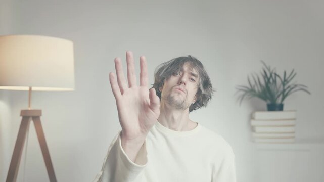 Young man showing stop gesture, boundary and refusal concept, indoor lifestyle portrait