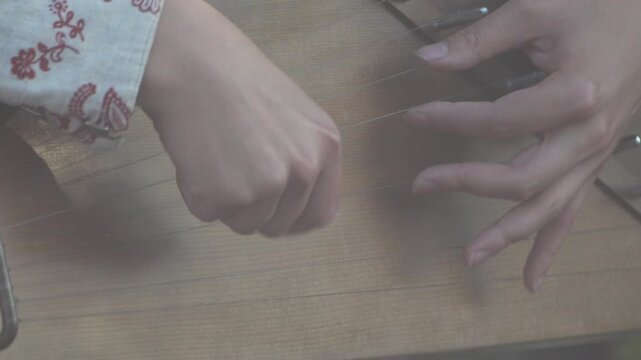 Hands playing traditional stringed instrument, folk music performance