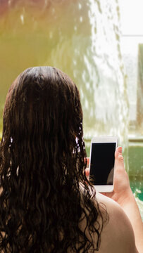woman relaxing and looking at a phone in the pool in a spa center