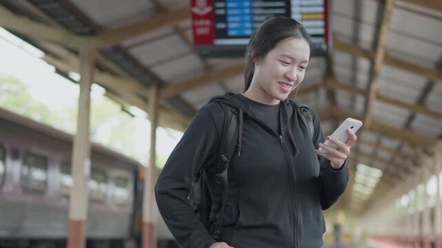 Traveler using a smartphone at a train station, ideal for travel app, online ticket, navigation, railway journey, tourism, public transport and trip planning concepts