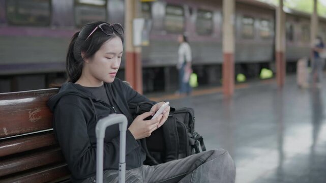 Traveler using a smartphone at a train station, ideal for travel app, online ticket, navigation, railway journey, tourism, public transport and trip planning concepts