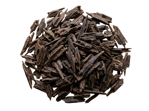 Pile of dark brown agarwood chips arranged in a circular shape isolated on a solid black background for aromatherapy and incense use