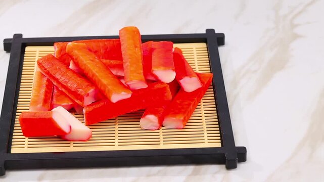 Fresh crab sticks rest on a bamboo tray.