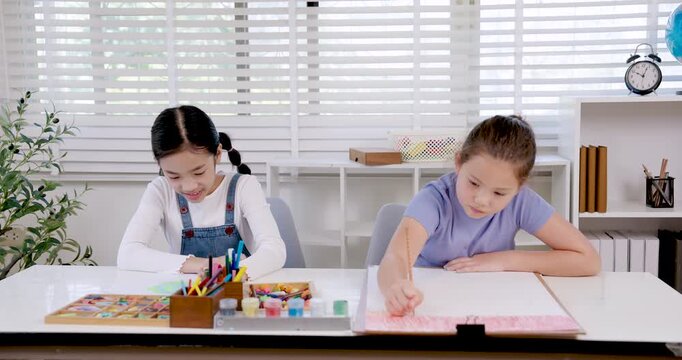 asian girl elementary student smiling while working on drawing project with colored pencil during classroom education lesson concentration on notebook creativity learning childhood study moment