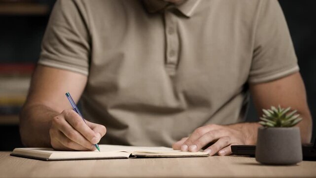 Businessman or Student Writing on Paper at Work Desk