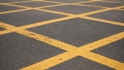 Obraz premium Yellow crosshatch no stopping road markings on dark asphalt.