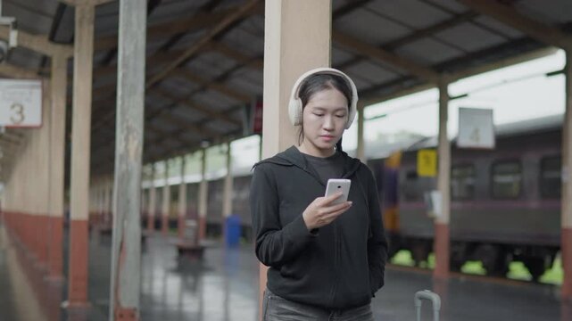 Traveler using a smartphone at a train station, ideal for travel app, online ticket, navigation, railway journey, tourism, public transport and trip planning concepts
