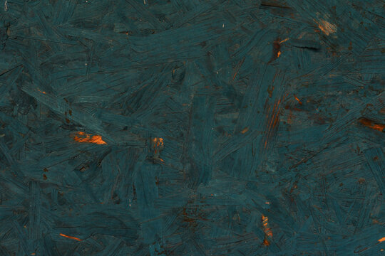 Dark teal painted chipboard surface with rough wood chipboard strands, scratches, layered texture. Suitable for abstract background, construction material detail, design resource, moody craft design