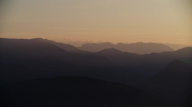 Breathtaking sunrise over the misty mountain peaks of Alpino di Stresa, Italy. Golden hour light illuminating the alpine ridges and foggy valleys