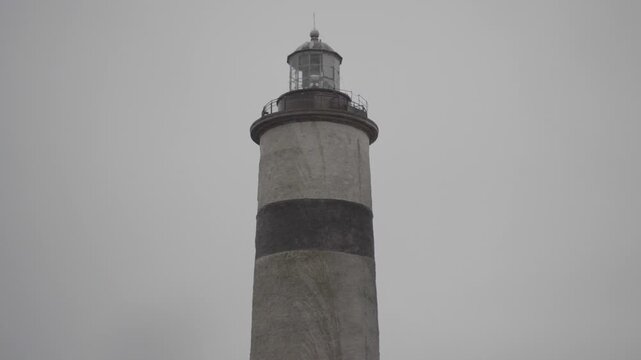 A coastal lighthouse in Falkenberg on a rainy, overcast day. Dramatic weather and muted tones emphasize a moody maritime atmosphere, highlighting isolation, navigation and raw power