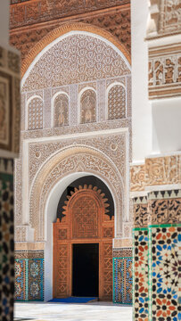 the central pool entrance facade showing complex hand-carved arabesque stucco panels in Ben Youssef Madrasa, Marrakech