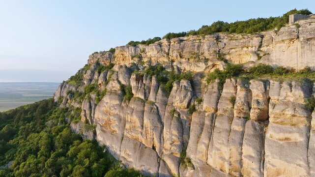 Madara rock ridge aerial drone view UNESCO Bulgaria limestone cliff green forest golden light slow motion travel tourism heritage landmark Shumen region scenic landscape