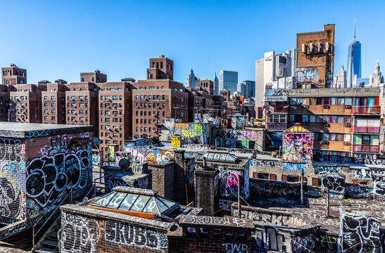 Graffiti-covered urban rooftops frame the dense Manhattan skyline in Chinatown, capturing the vibrant street art culture of an urban exploration destination in Lower Manhattan, New York City.
