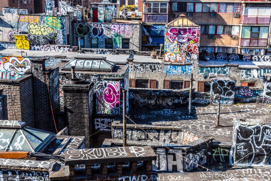 Graffiti street art adorns industrial rooftops in a dense urban environment in Chinatown  capturing the essence of city exploration and gritty culture in Lower Manhattan, New York City, USA.
