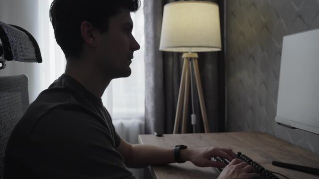 Man Working at Computer and Turning On Floor Lamp at Home