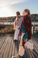 Fototapeta premium Two young women walking on a boardwalk, capturing authentic fashion and everyday coastal style