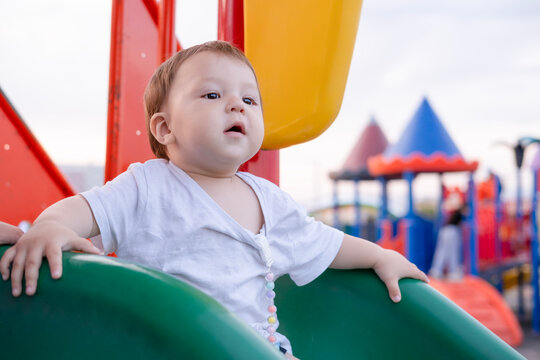 Portrait of a serious little toddler playing on a colorful outdoor playground