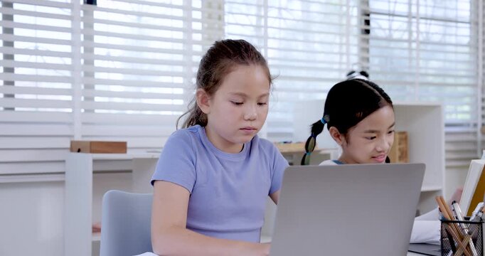 Caucasian preteen girl typing on laptop during slowmotion classroom activity with asian girl nearby symbolizing digital learning communication education teamwork productivity research collaboration
