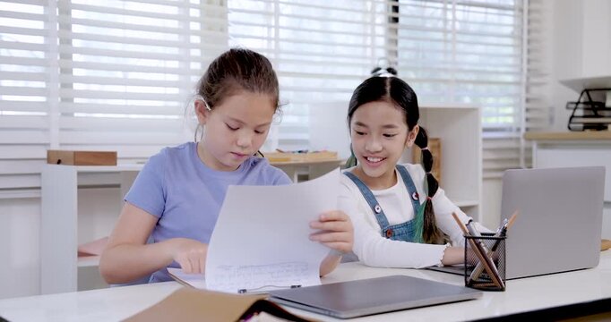 Asian girl preteen smiling while caucasian girl preteen student reading assignment paper during classroom teamwork collaboration project study digital education research communication learning