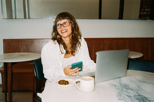 Young business person working remotely with coffee and laptop