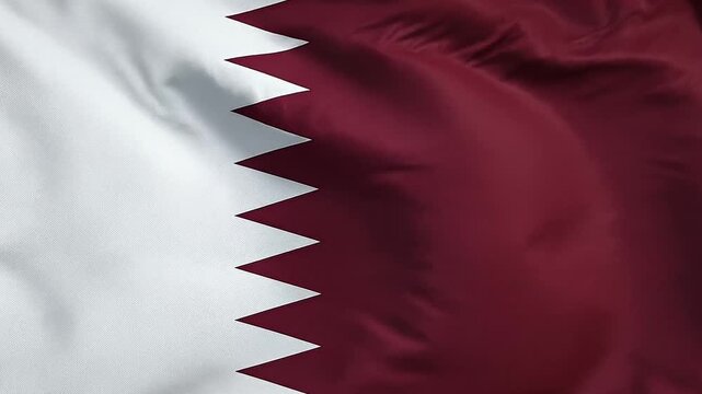 Close up of the national flag of Qatar waving in the wind, showing its distinct maroon and white serrated pattern