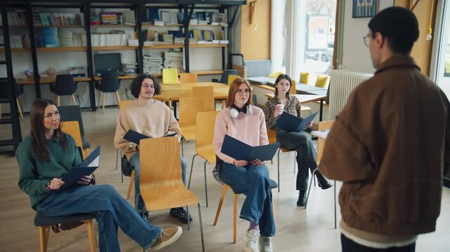 Group of students engaged in a learning session in a library while a teacher gives instructions and guidance